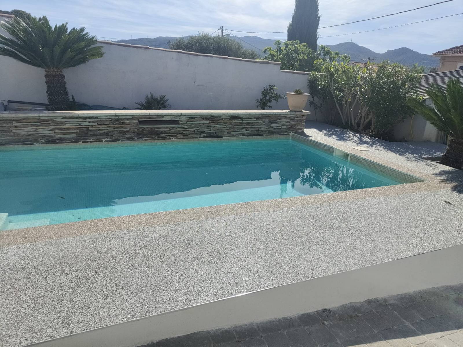 Contour de piscine en moquette de pierre dont une bande et de couleur beige avec un dégradé de gris pour sublime l'allé de cette maison qui ce situe sur Plan de Cuques Marseille 13013éme  
